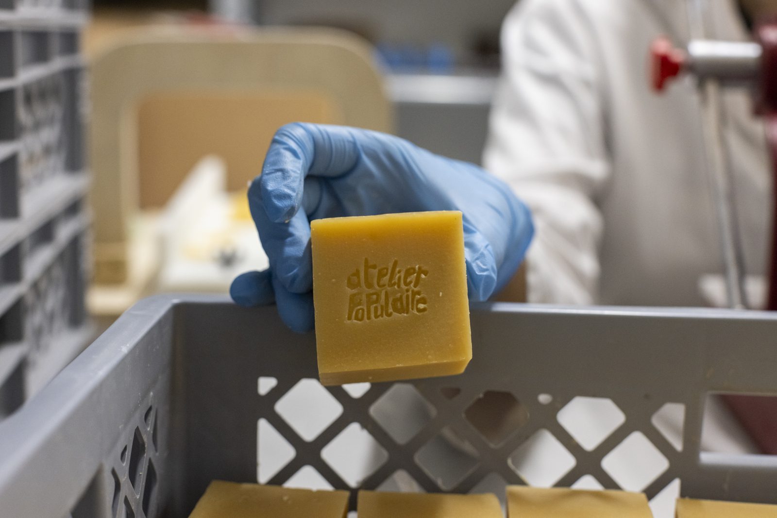 A gloved hand holds an Atelier Populaire soap at the workshop